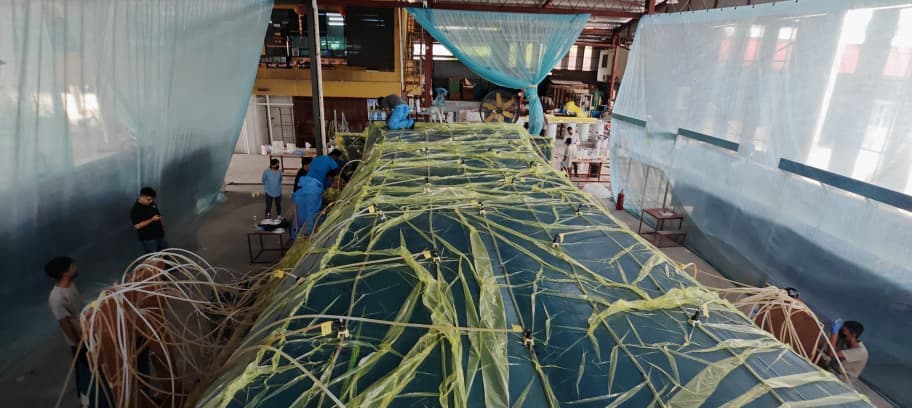 Resin infusion in progress on a long hull section — vacuum bag and flow media visible